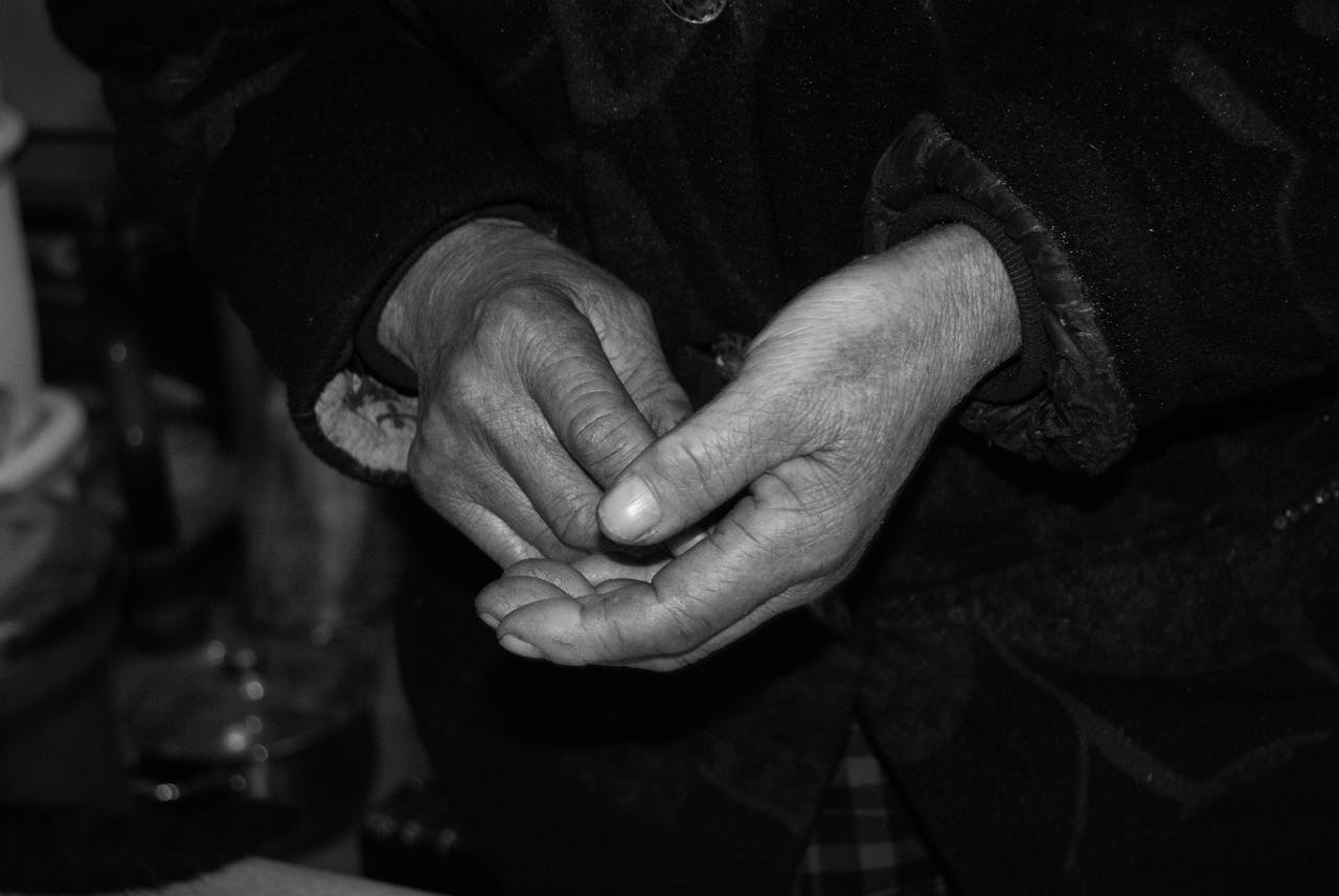 our-experience Close-up of elderly hands, weathered and expressive, captured in black and white.