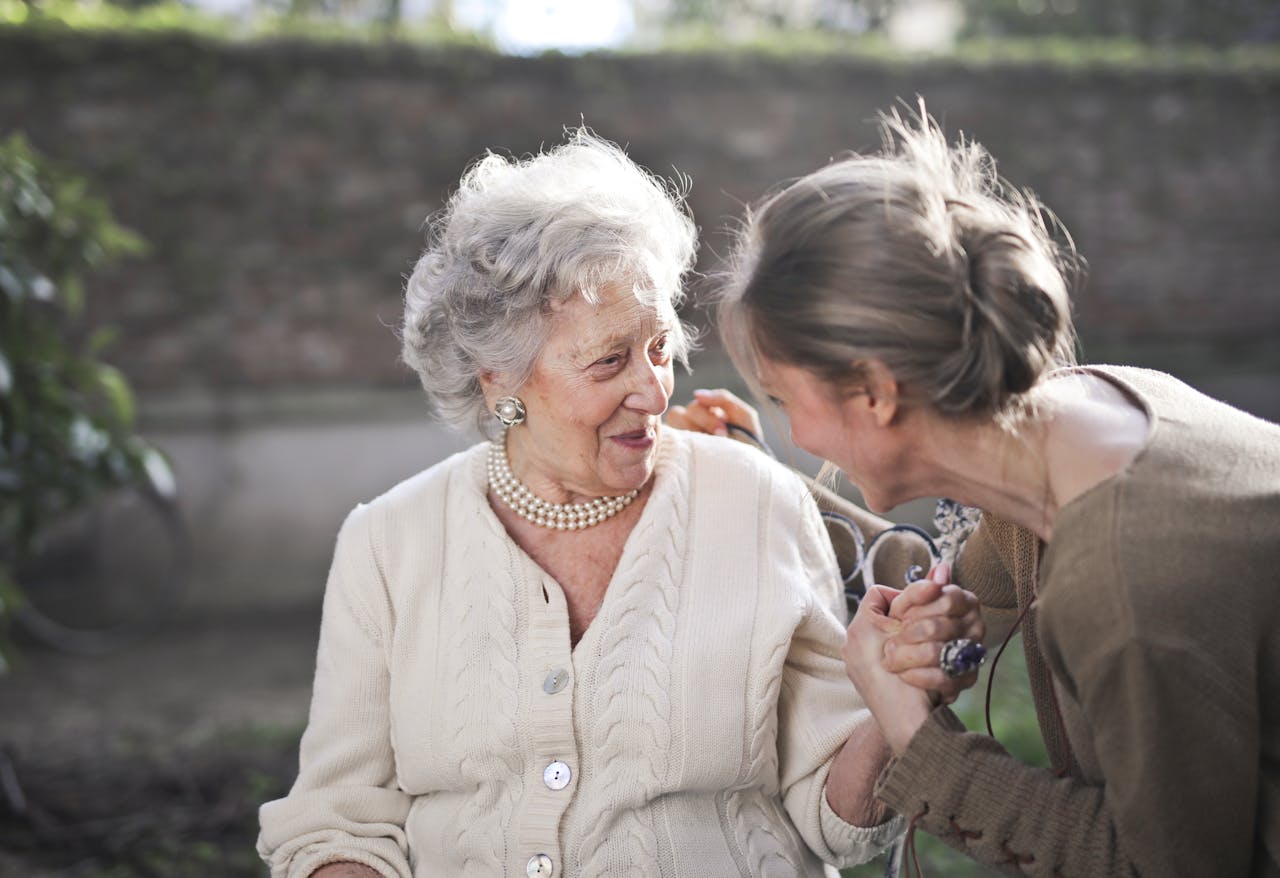 about-02 Joyful interaction between an elderly woman and her granddaughter in a sunny outdoor setting.